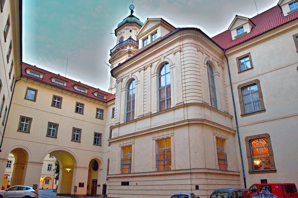 Un'ala color crema del Klementinum con alte finestre ad arco attorno a un cortile, e la Torre Astronomica dietro di essa