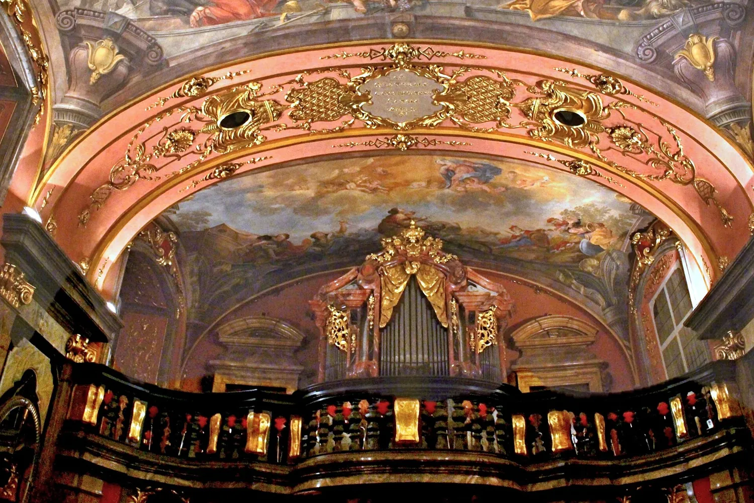 La cantoria della Cappella degli Specchi con una balaustra nera e dorata, un organo barocco e un soffitto dipinto sopra di essa